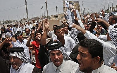 Family members of Diaa Mutashar al-Issawi, seen in the poster, chant anti-Jabhat al-Nusra and Free Syrian Army slogans during his funeral in Basra on Monday. (photo credit: AP/ Nabil Al-Jurani)