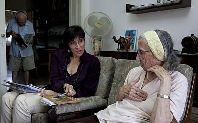 Holocaust survivor Rivka Fringeru, 82, right, holds her chest as she speaks to Cynthia Wroclawski, director of the Yad Vashem names collection project, Sunday, May 5, 2013. (photo credit: AP/Ariel Schalit)