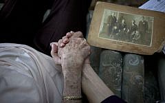 Holocaust survivor Rivka Fringeru, 82, left, holds hand with Cynthia Wroclawski, director of the Yad Vashem names collection project, Sunday, May 5, 2013 (photo credit: AP/Ariel Schalit)