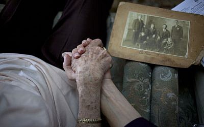 Holocaust survivor Rivka Fringeru, 82, left, holds hand with Cynthia Wroclawski, director of the Yad Vashem names collection project, Sunday, May 5, 2013 (photo credit: AP/Ariel Schalit)