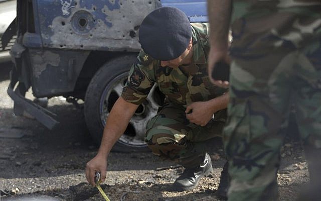 A Lebanese army officer investigates part of a rocket which struck a car exhibit on a street at the Mar Mikhael district, south of Beirut, Lebanon, Sunday May 26, 2013 (photo credit: AP/Hussein Malla) A Lebanese army officer investigates part of a rocket which struck a car exhibit on a street at the Mar Mikhael district, south of Beirut, Lebanon, Sunday May 26, 2013 (photo credit: AP/Hussein Malla)
