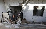 A Lebanese investigator takes pictures at a balcony where a rocket struck an apartment in a building at Chiyah district, south of Beirut, Lebanon, Sunday May 26, 2013 (photo credit: AP/Hussein Malla)