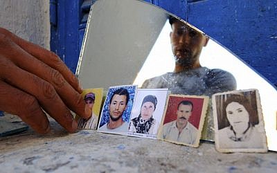 Issam Khedri, 29, eldest brother of cigarette vendor Adel Khedri, shows photos of, from left, his brother Adel, his mother, Latifa, and his father, Habib, in his room in the Mellassine slum of the Tunisian capital, Tunis. Born in Souk al-Jumma, about 150 kilometers west of Tunis, Habib went to the capital as a young man to find work as a day laborer. (AP Photo/Ons Abid)