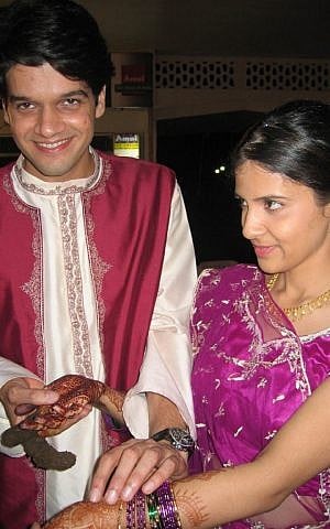As a part of the mehndi ceremony, David looks for his name, which is written in henna on Aviva’s hand. (photo credit: Paul Dharamraj and Ofira Reuben/Times of Israel)