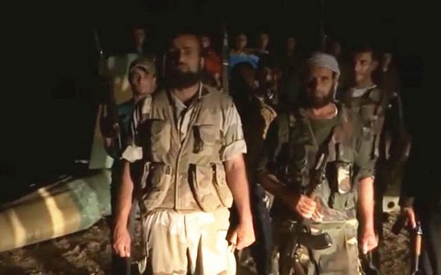 Syrian rebels stand before what they claim is a downed regime helicopter. (photo credit: image capture YouTube/Syrian Observatory for Human Rights)