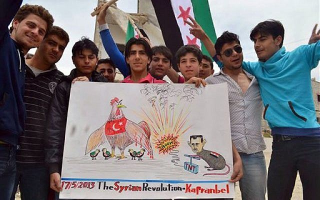 Anti-Syrian regime protesters holding a placard with a caricature of Syrian President Bashar Assad during a demonstration in Kafr Nabil, in Idlib province, northern Syria, Friday, May 17, 2013.(photo credit: AP Photo/Edlib News Network ENN)