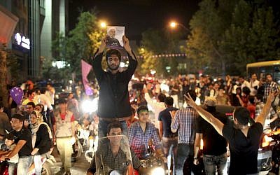A supporter of Hasan Rowhani holds up his poster while celebrating Rowhani's victory in Tehran on Saturday. (photo credit: AP/Ebrahim Noroozi)