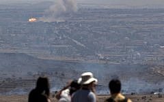 Israelis and tourists look at a fire, caused by fighting in Syria, from an observation point on Mt. Bental in the Golan Heights, near the border between the Golan Heights and Syria, Friday, June 7, 2013. (photo credit: AP/Sebastian Scheiner)