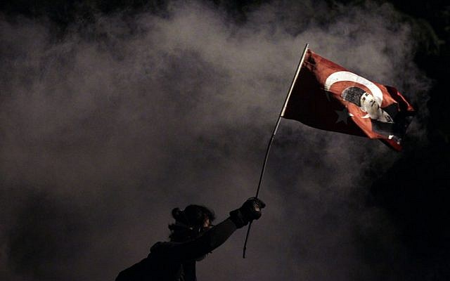 A protester holds a Turkish flag decorated with the image of Turkey's founder Mustafa Kemal Ataturk, during clashes near Taksim Square in Istanbul, late Monday, June 3, 2013 (photo credit: AP/Kostas Tsironis) A protester holds a Turkish flag decorated with the image of Turkey's founder Mustafa Kemal Ataturk, during clashes near Taksim Square in Istanbul, late Monday, June 3, 2013 (photo credit: AP/Kostas Tsironis)
