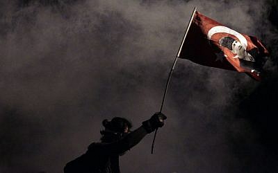 A protester holds a Turkish flag decorated with the image of Turkey's founder Mustafa Kemal Ataturk, during clashes near Taksim Square in Istanbul, Monday (AP Photo/Kostas Tsironis)