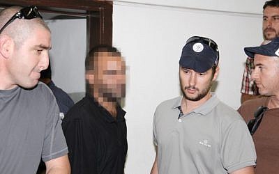 A suspect related to the 2009 Bar Noar shooting attack is escorted by police as he arrives in court in Tel Aviv, on Thursday. (photo credit: Flash90)