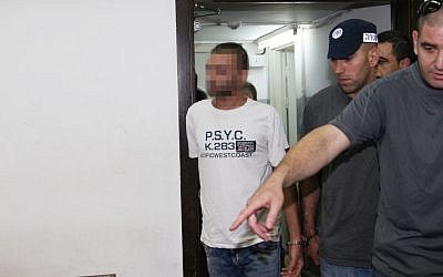 A suspect related to the 2009 Bar Noar shooting attack is escorted by police as he arrives in court in Tel Aviv, on Thursday (photo credit: Flash90)