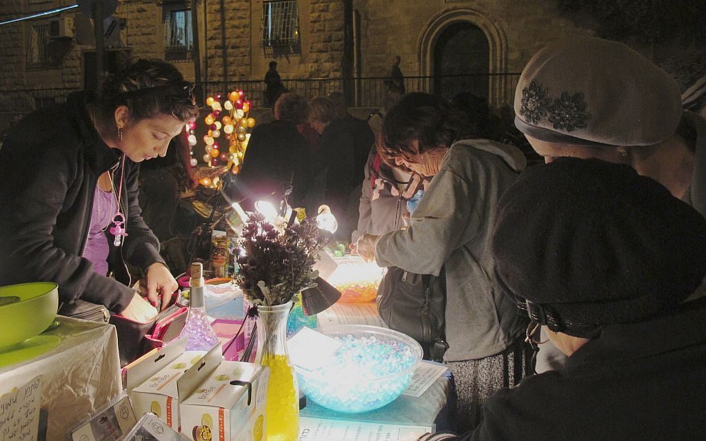 Local merchants take the opportunity to engage with light show participants, selling beads, lamps and other shiny, light-related objects (photo credit: Leeor Bronis/Times of Israel)