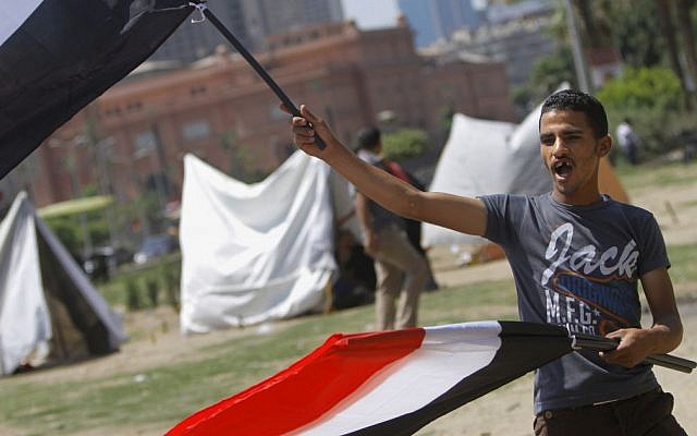 An Egyptian flag vendor waves flags in front of new erected strike tents in Tahrir Square, the focal point of Egyptian uprising in Cairo, Egypt, Saturday, June 22, 2013. (photo credit: AP/ Amr Nabil) An Egyptian flag vendor waves flags in front of new erected strike tents in Tahrir Square, the focal point of Egyptian uprising in Cairo, Egypt, Saturday, June 22, 2013. (photo credit: AP/ Amr Nabil)