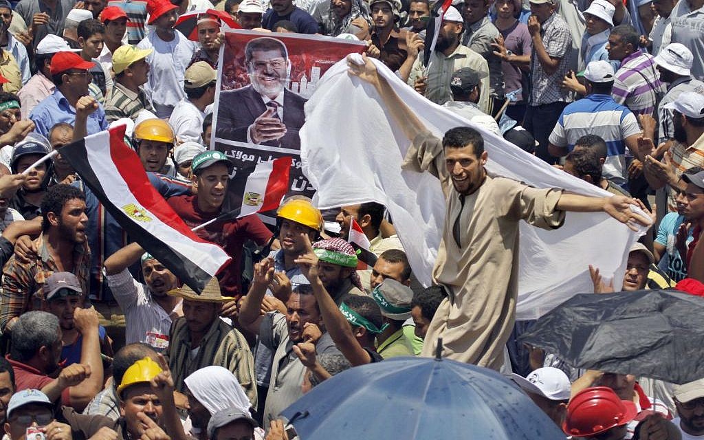 An Egyptian supporter of Egypt's Islamist President Mohammed Morsi dances by a poster of Morsi during a rally outside the Rabia el-Adawiya mosque near the presidential palace in Cairo, Saturday, June 29 (photo credit: APAmr Nabil)