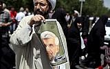 An Iranian cleric holds up a poster of presidential candidate Saeed Jalili, Iran's top nuclear negotiator, after the Friday prayer in Tehran, Friday, May 31, 2013. Iranians have seen it before: A youngish presidential candidate firing up crowds with fist-waving rants against the West, then displaying his Islamist bona fides with courtesy calls to hard-line clerics. (AP Photo/Ebrahim Noroozi)