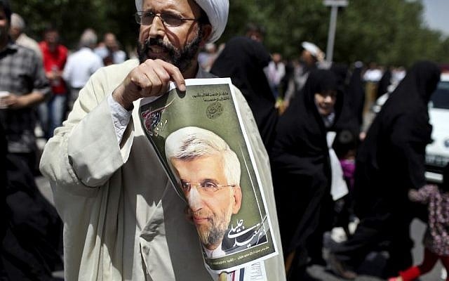 An Iranian cleric holds up a poster of presidential candidate Saeed Jalili, Iran's top nuclear negotiator, after the Friday prayer in Tehran, Friday, May 31, 2013. Iranians have seen it before: A youngish presidential candidate firing up crowds with fist-waving rants against the West, then displaying his Islamist bona fides with courtesy calls to hard-line clerics. (AP Photo/Ebrahim Noroozi) An Iranian cleric holds up a poster of presidential candidate Saeed Jalili, Iran's top nuclear negotiator, after the Friday prayer in Tehran, Friday, May 31, 2013. Iranians have seen it before: A youngish presidential candidate firing up crowds with fist-waving rants against the West, then displaying his Islamist bona fides with courtesy calls to hard-line clerics. (AP Photo/Ebrahim Noroozi)