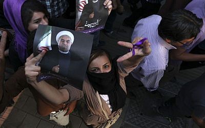 A female supporter of Hasan Rowhani flashes a victory sign as she holds his poster during a celebration gathering in Tehran, Saturday, June 15, 2013. Rowhani was declared the winner of Iran's presidential vote. (photo credit: AP Photo/Vahid Salemi)
