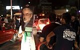 A supporter of Iranian presidential candidate Hasan Rouhani holds up a poster of Green Movement leader Mir Hossein Mousavi, while celebrating Rouhani's victory, in Tehran, Saturday, June 15, 2013.  (AP/Ebrahim Noroozi)