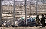 African refugees sit behind a border fence after they attempted to cross illegally from Egypt into Israel as Israeli soldiers stand guard near the border with Egypt, in southern Israel, on September 4, 2012. (AP/Ariel Schalit, File)