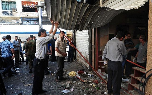 In this photo released by the Syrian official news agency SANA, Syrians inspect a damaged shop at a scene of two explosions in the central district of Marjeh, Damascus, Syria, Tuesday, June 11, 2013 (photo credit: AP/SANA)