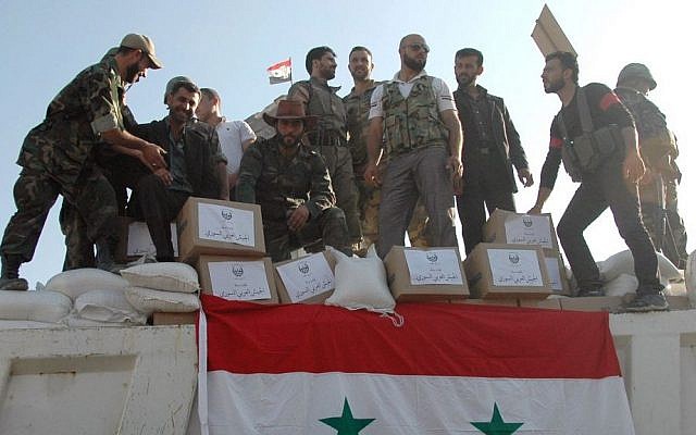 Syrian soldiers loyal to President Bashar Assad stand on a truck full of aid supplies, in Qusair, Syria, June 5, 2013. (photo credit: AP/SANA/File) Syrian soldiers loyal to President Bashar Assad stand on a truck full of aid supplies, in Qusair, Syria, June 5, 2013. (photo credit: AP/SANA/File)