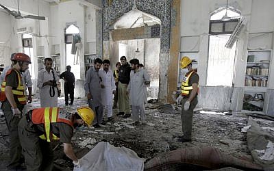 Pakistani volunteers cover a lifeless body following a suicide bombing at a Shiite mosque in Peshawar, Pakistan on Friday, June 21 (photo credit: AP/Mohammad Sajjad)