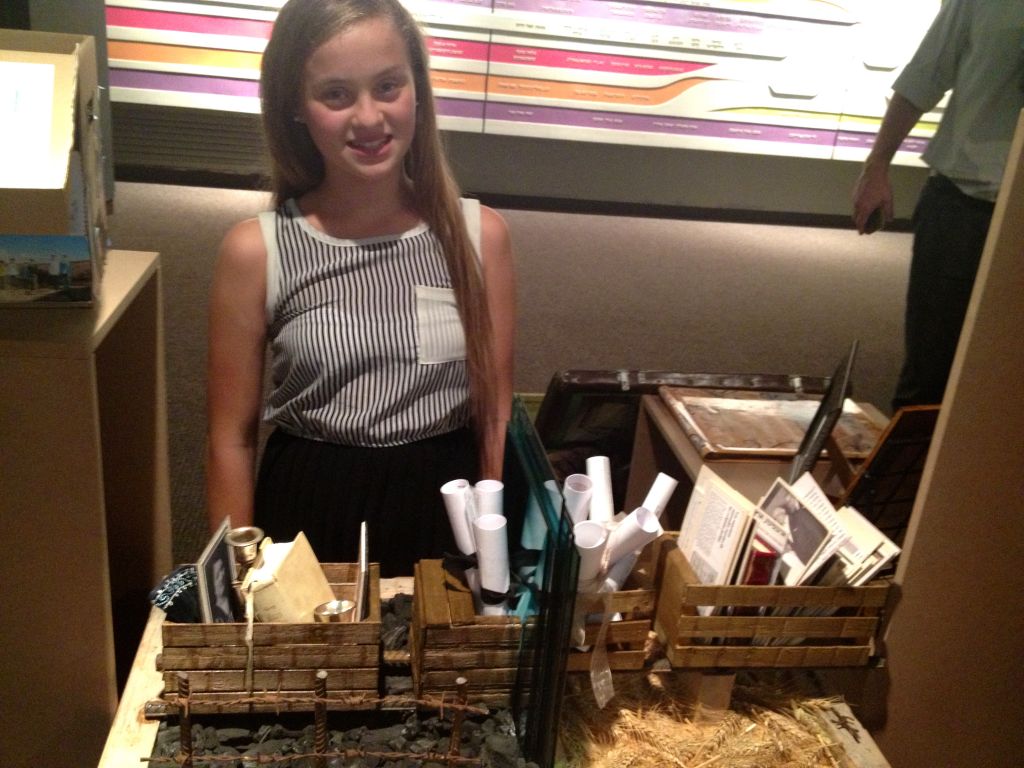 Roni Heimberg,12, a student from the Yahalom School in Shoham, poses with her first-place winning display for 'My Family Story,' a competition held by the Beit Hatfutsot, the Museum of the Jewish People (photo credit: Leeor Bronis/Times of Israel)