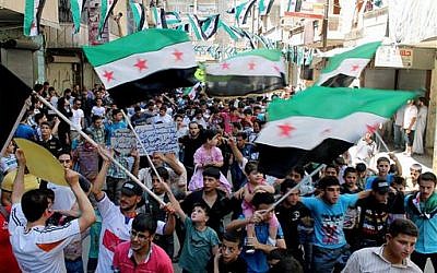 Anti-Syrian regime protesters holding Syrian revolution flags, during a demonstration in the neighborhood of Bustan Al-Qasr in Aleppo, Syria, Friday, June 28, 2013 (photo credit: AP Photo/Aleppo Media Center AMC)