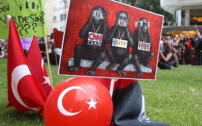 In this Sunday, June 2, 2013 photo protesters display a banner depicting Turkish media as the three wise monkeys who see no evil, speak no evil and hear no evil, outside Haber Turk television channel in Istanbul.(photo credit: AP/Thanassis Stavrakis)