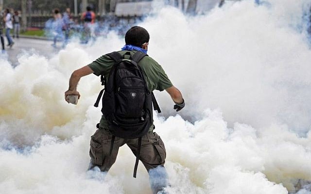A man runs as riot police use tear gas and pressurized water to quash a sit-in protest to try and prevent the demolition of trees at an Istanbul park, Turkey, Friday, May 31, 2013. Police moved in at dawn Friday to disperse the crowd on the fourth day of the protest against a contentious government plan to revamp Istanbul’s main square, Taksim. (AP Photo)