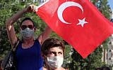 A young woman waves a national flag at paramilitary police at the entrance of a road leading to the prime minister's office as Turkish youths shout 'Tayyip, resign!' and clash with security forces in Ankara, Turkey, Saturday, June 1, 2013 (photo credit: AP/Orhan Ozbilici)