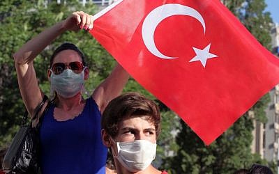 A young woman waves a national flag at paramilitary police at the entrance of a road leading to the prime minister's office as Turkish youths shout 'Tayyip, resign!' and clash with security forces in Ankara, Turkey, Saturday, June 1, 2013 (photo credit: AP/Orhan Ozbilici)