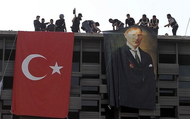 Police hang a banner of Mustafa Kemal Ataturk, founder of the modern Turkey, next to a Turkish flag in a cultural center during a police operation to evacuate Taksim Square in Istanbul Tuesday, June 11, 2013. (Photo credit: AP/Thanassis Stavrakis)