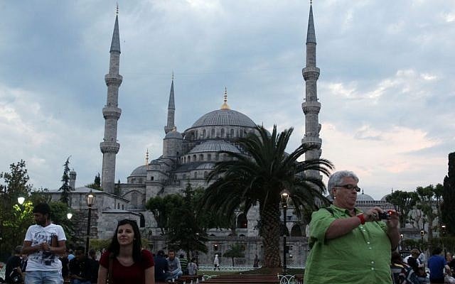 Tourists take photographs in front of the Blue Mosque in Sultanahmet tourist area of Istanbul, late Tuesday, on June 4, 2013. (photo credit: AP Photo/Thanassis Stavrakis)