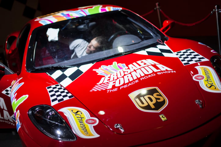 A worker cleans a Ferrari racing car as he prepares it for display prior to the opening of a racing car and motorcycle exhibition held at the Old Jerusalem Train Station, on June 9, 2013 (photo credit: Flash90)
