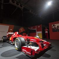 A Ferrari technical crew member stands next to a Ferrari Formula One racing car, on display during a racing car and motorcycle exhibition held at the Old Jerusalem Train Station, on June 9, 2013 (photo credit: Flash90)