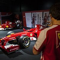 A Ferrari technical crew member takes a photograph of Ferrari Formula One racing cars, on display during a racing car and motorcycle exhibition held at the Old Jerusalem Train Station, on June 9, 2013 (photo credit: Flash90)