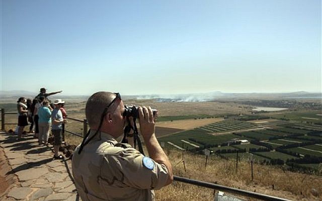 A UN soldier looks through binoculars towards Syria from an observation point on Mt. Bental in the Golan Heights as smoke rises from nearby fighting in Syria, Friday, June 7, 2013 (photo credit: AP Photo/Sebastian Scheiner) A UN soldier looks through binoculars towards Syria from an observation point on Mt. Bental in the Golan Heights as smoke rises from nearby fighting in Syria, Friday, June 7, 2013 (photo credit: AP Photo/Sebastian Scheiner)
