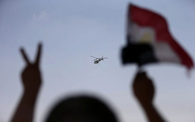 A police helicopter flies over the presidential palace, as a man waves the Egyptian national flag , in Cairo, Egypt, Tuesday, July 2 (photo credit: AP/Hassan Ammar) A police helicopter flies over the presidential palace, as a man waves the Egyptian national flag , in Cairo, Egypt, Tuesday, July 2 (photo credit: AP/Hassan Ammar)