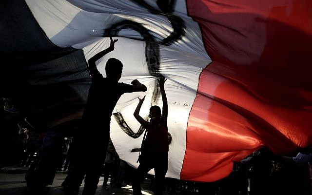 Opponents of Egypt's Islamist President Mohammed Morsi hold a large Egyptian national flag during a protest outside the presidential palace, in Cairo, Egypt, Tuesday, July 2, 2013 (photo credit: AP/Hassan Ammar) Opponents of Egypt's Islamist President Mohammed Morsi hold a large Egyptian national flag during a protest outside the presidential palace, in Cairo, Egypt, Tuesday, July 2, 2013 (photo credit: AP/Hassan Ammar)