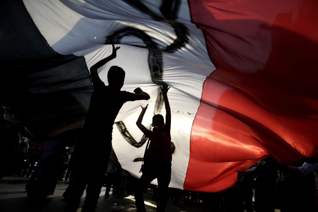 Opponents of Egypt's Islamist President Mohammed Morsi hold a large Egyptian national flag during a protest outside the presidential palace, in Cairo, Egypt, Tuesday, July 2, 2013 (photo credit: AP/Hassan Ammar) Opponents of Egypt's Islamist President Mohammed Morsi hold a large Egyptian national flag during a protest outside the presidential palace, in Cairo, Egypt, Tuesday, July 2, 2013 (photo credit: AP/Hassan Ammar)