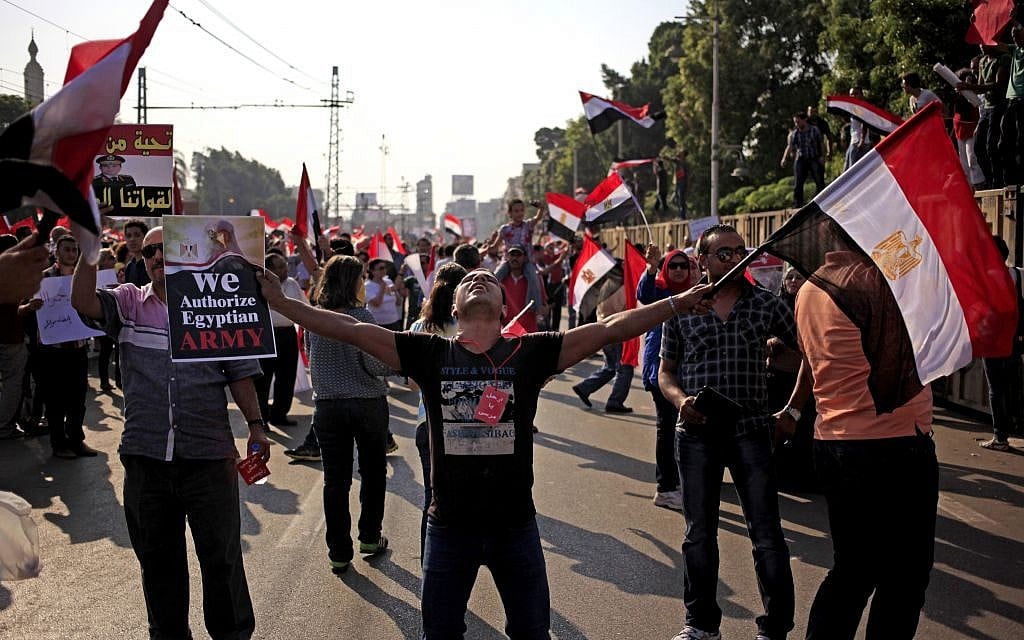 Opponents of Egypt's Islamist President Mohammed Morsi wave national flags during a protest outside the presidential palace on Wednesday. (Photo credit: AP/Khalil Hamra)