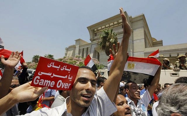 Egyptians celebrate after Egypt's chief justice Adly Mansour is sworn in as the nation's interim president on Thursday, July 4, 2013. Arabic reads, " bye bye Morsi." (photo credit: AP Photo/Amr Nabil)