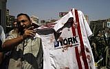 A supporter of ousted Egyptian President Mohammed Morsi stands outside a local hospital in Cairo holding a bloodied shirt he says belongs to a protester shot by soldiers during a demonstration, Monday, July 8, 2013 (photo credit: AP/Nasser Shiyoukhi)
