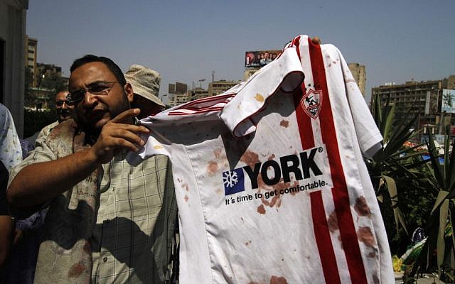 A supporter of ousted Egyptian President Mohammed Morsi stands outside a local hospital in Cairo holding a bloodied shirt he says belongs to a protester shot by soldiers during a demonstration, Monday, July 8, 2013 (photo credit: AP/Nasser Shiyoukhi) A supporter of ousted Egyptian President Mohammed Morsi stands outside a local hospital in Cairo holding a bloodied shirt he says belongs to a protester shot by soldiers during a demonstration, Monday, July 8, 2013 (photo credit: AP/Nasser Shiyoukhi)