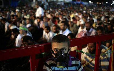 A boy wears a tear gas mask as supporters of Egypt's ousted resident Mohammed Morsi pray at Nasr City, in Cairo on July 28, 2013. (photo credit: Hassan Ammar/AP)
