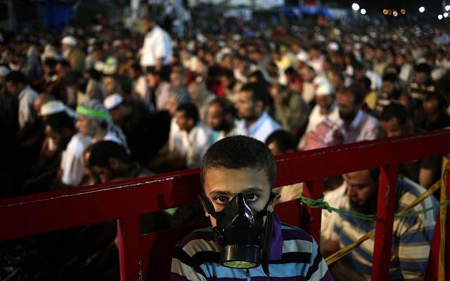 A boy wears a tear gas mask as supporters of Egypt's ousted resident Mohammed Morsi pray at Nasr City, in Cairo on July 28, 2013. (photo credit: Hassan Ammar/AP) A boy wears a tear gas mask as supporters of Egypt's ousted resident Mohammed Morsi pray at Nasr City, in Cairo on July 28, 2013. (photo credit: Hassan Ammar/AP)