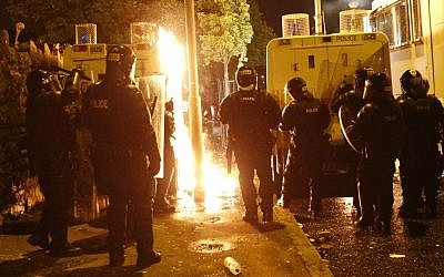 Riot police watch flames of Molotov cocktails thrown by Protestant hardliners in North Belfast, Northern Ireland, early Saturday. (photo credit: AP/Peter Morrison)