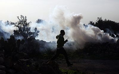 A young Palestinian boy running away from tear gas during a protest against Israel's security barrier in the West Bank Village of Na'alin (photo credit: Matanya Tausig/Flash90)